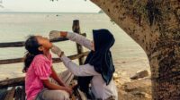 vaksin Rani Amsa, bidan dari Puskesmas Peukan Bada, memberikan imunisasi polio di dekat pantai di Aceh Besar, Aceh, saat Pekan Imunisasi Nasional pada bulan Desember 2022. Foto: WHO/Fauzan Ijazah